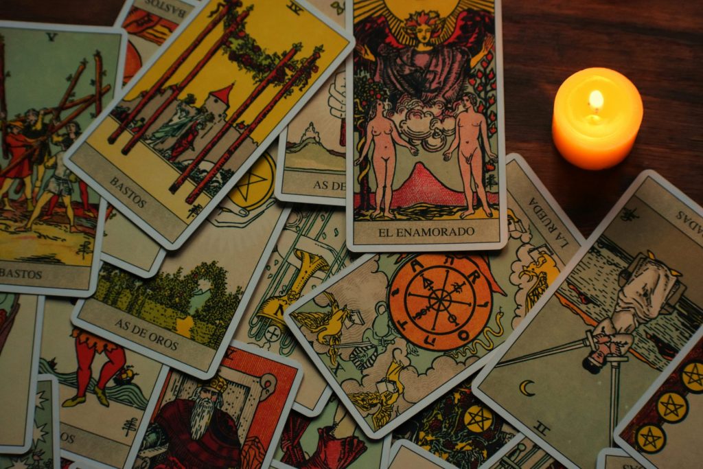 une bougie posée à côté d'une pile de cartes de tarot